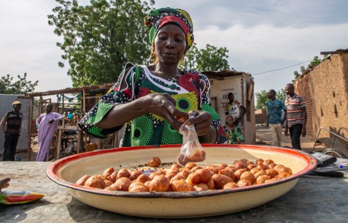 Woman smiling widely behind bags of peanuts.