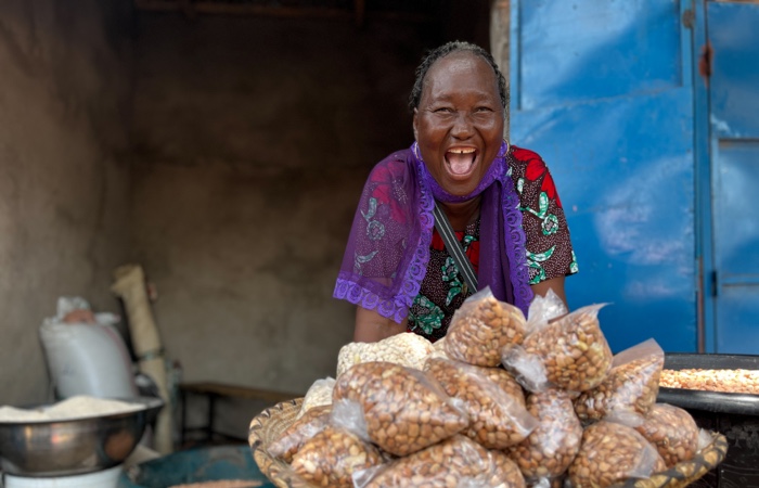 Woman smiling widely behind bags of peanuts.
