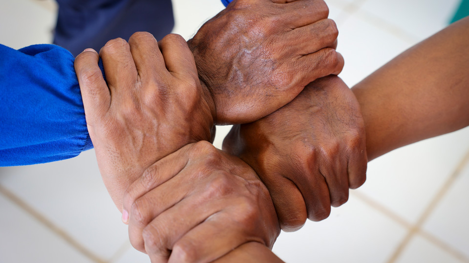 4 hands hold on to each other in a square.