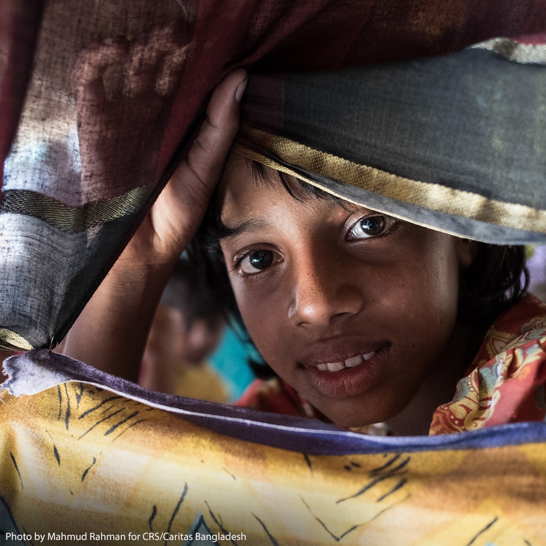 Child looks through blankets.