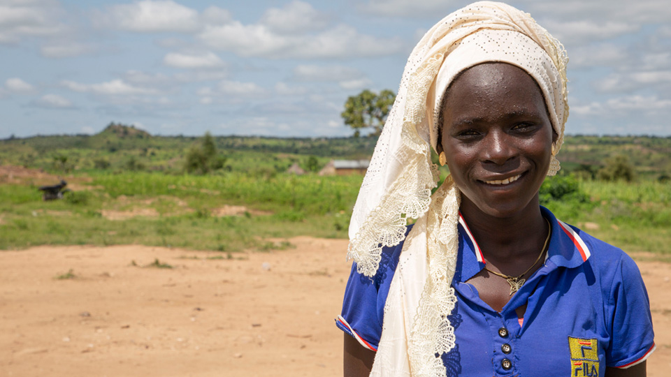 Young woman with white head scarf smiling.