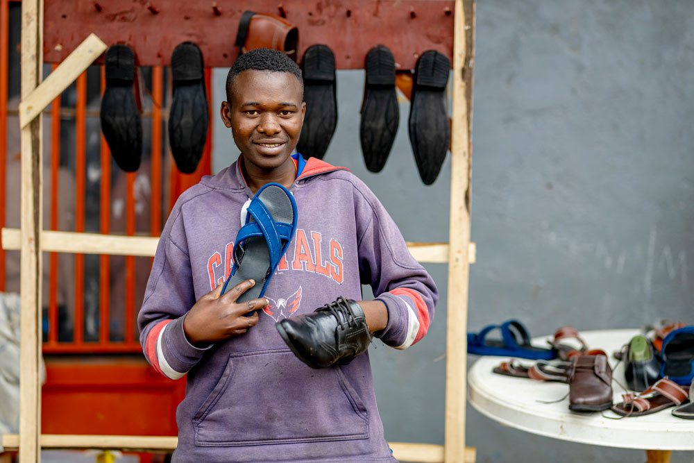 A young man standing in front of a shoe stand.