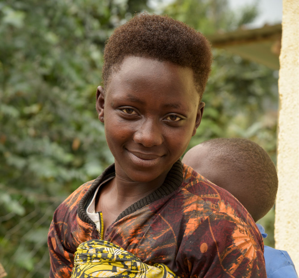A young girl carrying a child on his back.