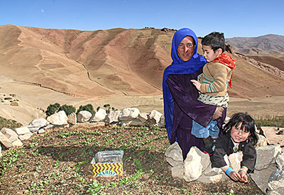Bonu and her two children pose by their keyhole garden, introduced to the region by CRS. The raised-bed garden was built with the help of friends and neighbors who used donkeys to carry stones up the steep mountainside. Photo by Jennifer Hardy/CRS
