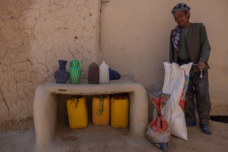 Afghan farmer standing near family food supply