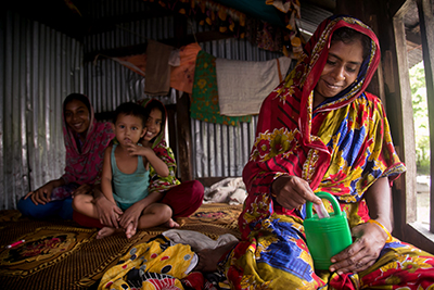 Rina Begum adds money to her family's savings box. CRS and Caritas Bangladesh are working with Rina's family to build a plan to bounce back from disasters. Photo by Jennifer Hardy/CRS