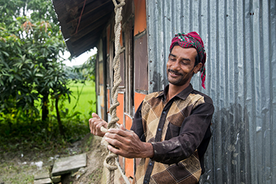Almas Sikdar ties a secure rope to a roof brace of his house, which will reduce flying debris and damage to his home during future storms. Photo by Jennifer Hardy/CRS