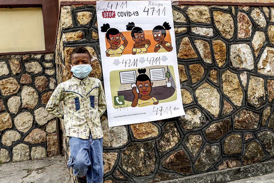 boy stands near covid poster in DR Congo