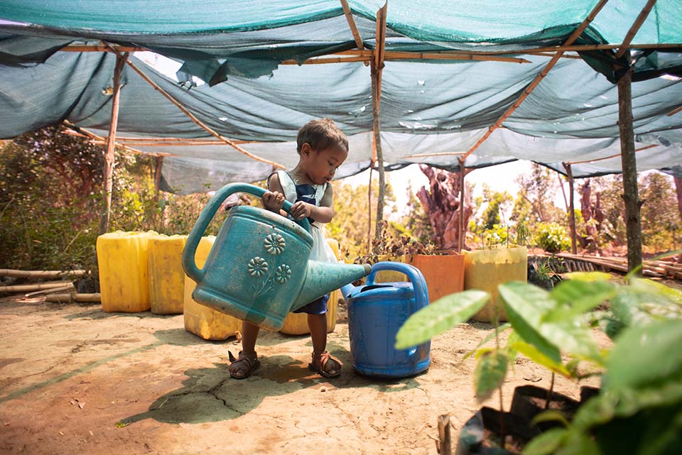 child helps water plants in Madagascar 