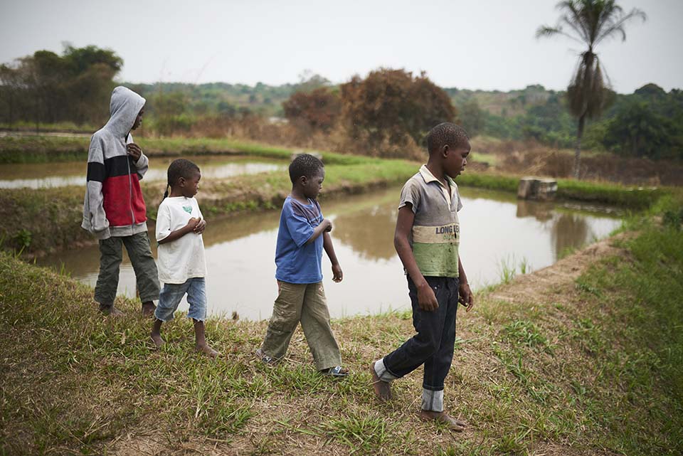 children in Republic of Congo walk past pond