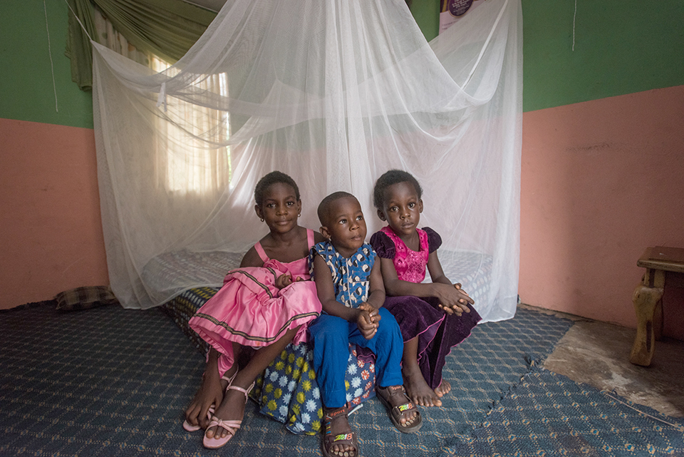 children sit in front of bed net