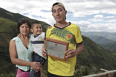 Fidencio Chamorro, with his wife and son in Colombia, displays the Borderlands certificate he received for growing the best coffee in 2013. Photo by Oscar Leiva/Silverlight for CRS