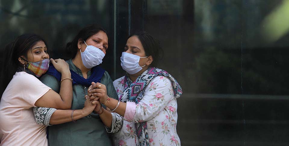 3 women in India wearing masks at crematorium