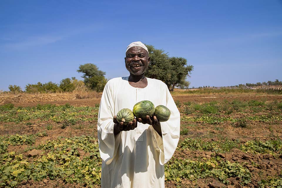 Darfur farmer holding melons facing camera