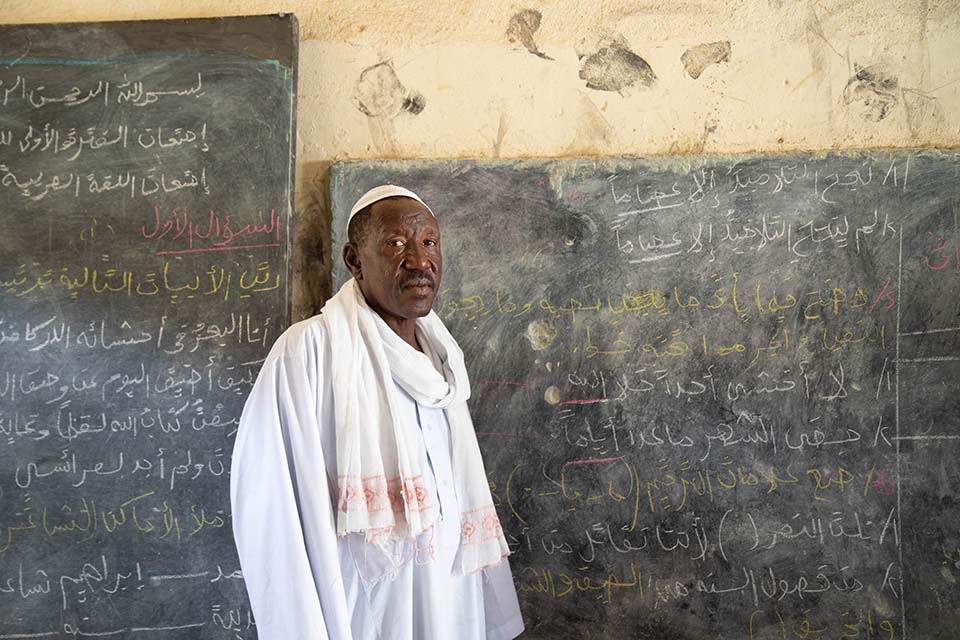 headmaster stands by chalkboard in Darfur