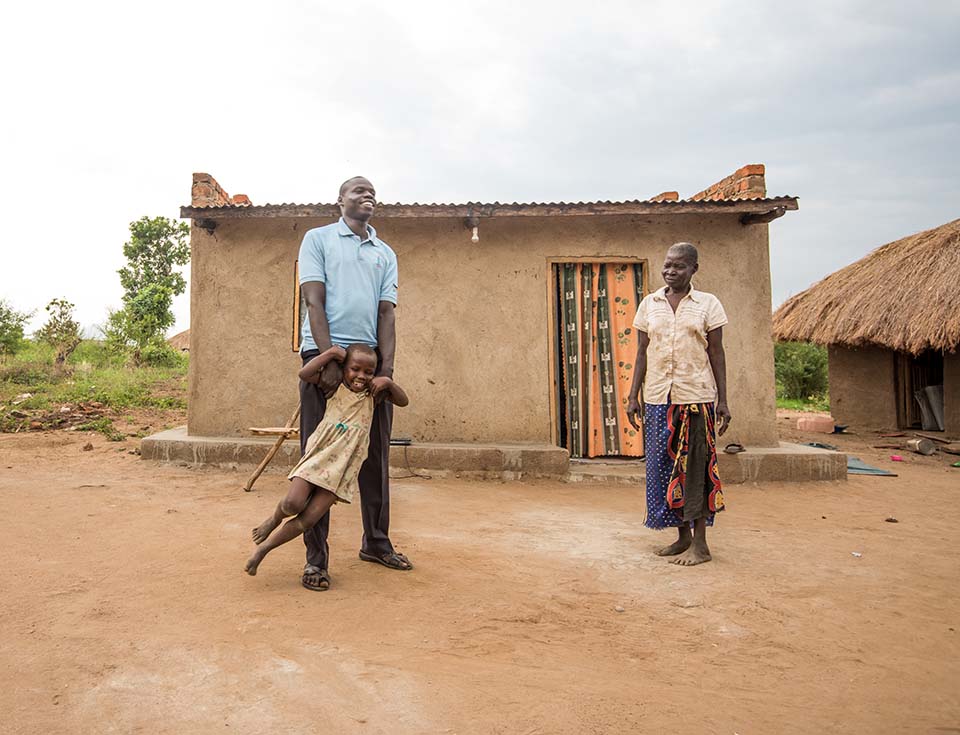 South Sudanese father plays with daughter outside their Uganda home