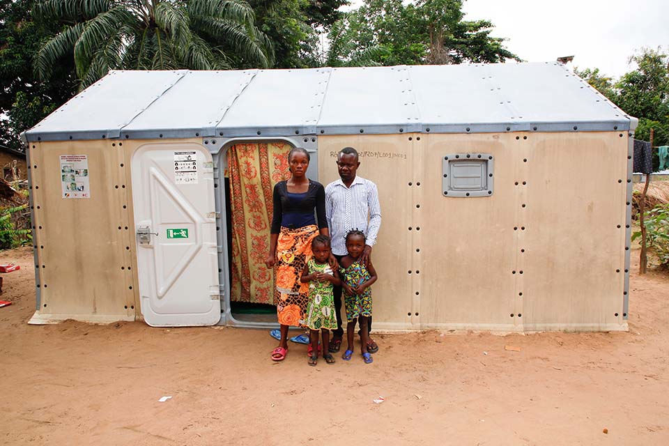 family stands outside their temporary home in Congo