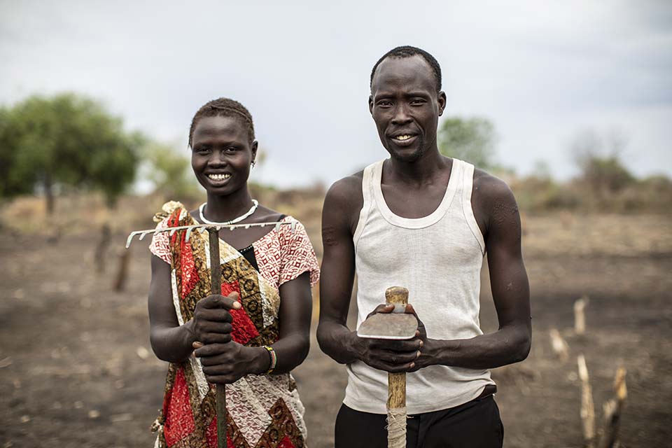 farming couple stand in a field in South Sudan