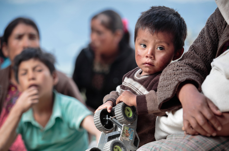 Javier plays while adults gather for a meeting about how to keep their children healthy and their families well fed through the CRS SEGAMIL program. Photo by Oscar Leiva/Silverlight for CRS