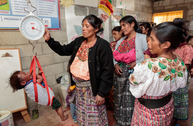 Audilia Ambrosio Ram'rez, 24, weighs a baby at a village health post in Guatemala, as part of an effort to end malnutrition and child mortality. Photo by Oscar Leiva/Silverlight for CRS