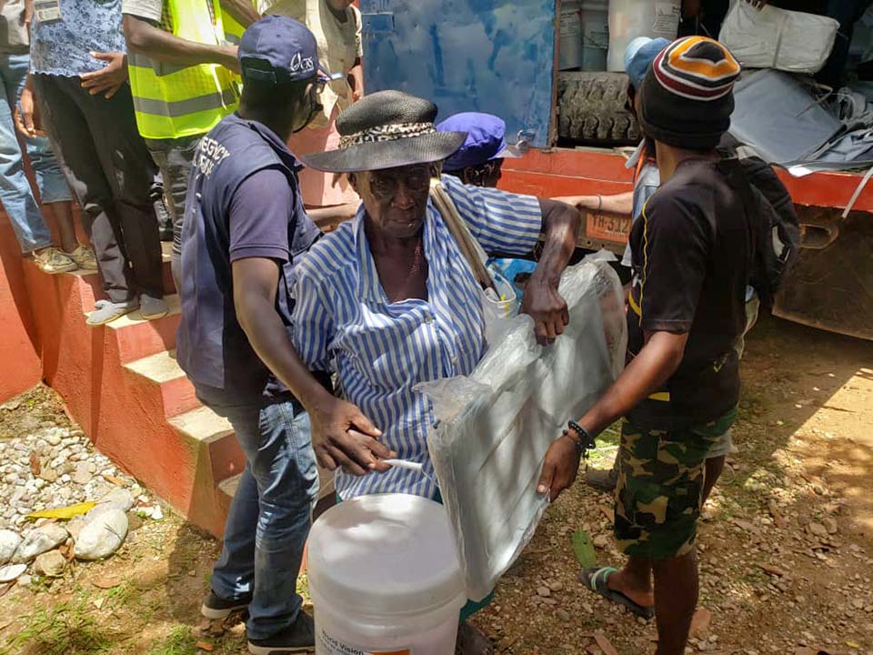 Haitian woman carries supplies at an emergency distribution point