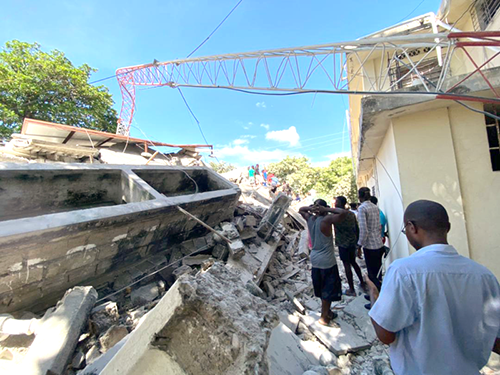 Haitians walk over rubble to survey earthquake damage to buildings