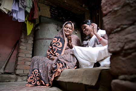 Sunita Devi, right, shares information—via a CRS-developed mobile phone app—that will help Sanchita, pregnant with her fourth child, deliver a healthy baby. Photo by Jennifer Hardy/CRS