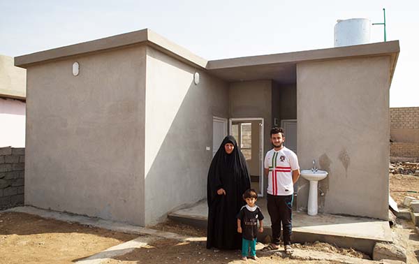 Iraq family stands outside rebuilt home