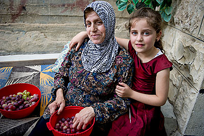 Intisar Atallah enjoys time with her granddaughter in the backyard of her West Bank home. Intisar receives a food voucher through a CRS program. Photo by Karen Kasmauski for CRS