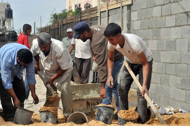Laborers repair shrapnel and bullet damage to the kindergarten through a CRS cash-for-work program. Photo by Shareef Sarhan for CRS