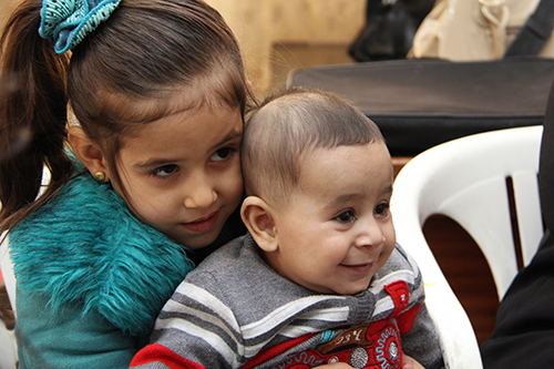 Rawan, 5—playing with her baby brother, Ahmad—attends a CRS-supported preschool for Syrian refugee children in Jordan. Her mother says the school has made her \"stronger.\" Photo by Kim Pozniak/CRS