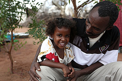 Photo by Sara A. Fajardo/CRS Farhiya, 4, helps her father, Ahmed Hussein, teach children in the Kambioos refugee camp in Kenya about the importance of hand-washing. Photo by Sara A. Fajardo/CRS