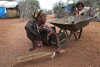 Twelve-year-old Iqra Hussein, left, cleans the compound outside her home with the help of her 4-year-old sister, Farhiya. Photo by Sara A. Fajardo/CRS