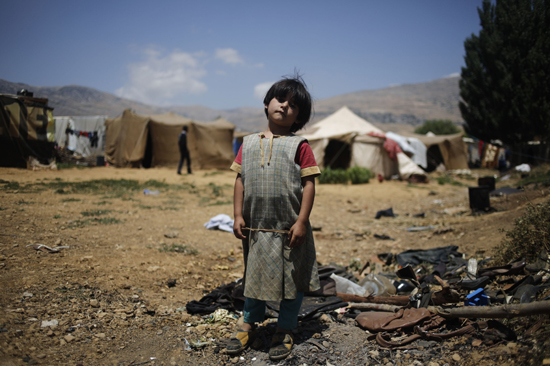 Seven-year-old Raghed, a Syrian refugee, stands on a trash pile at an informal refugee settlement in Lebanon's Bekaa Valley. Photo by Sam Tarling for CRS