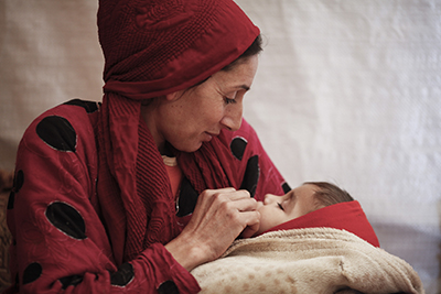 Syrian refugee Souad Mohamed with her baby, Hassan, inside the tent where they live in an informal settlement in Lebanon's Bekaa Valley. Photo by Sam Tarling for CRS