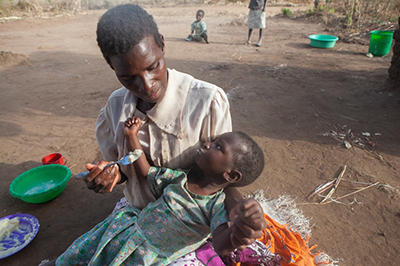 Teresa Kananji feeds her daughter Promisi, 3, a breakfast of warm porridge. Promisi suffered a stroke that left her paralyzed when she was 2½. Photo by Sara A. Fajardo/CRS