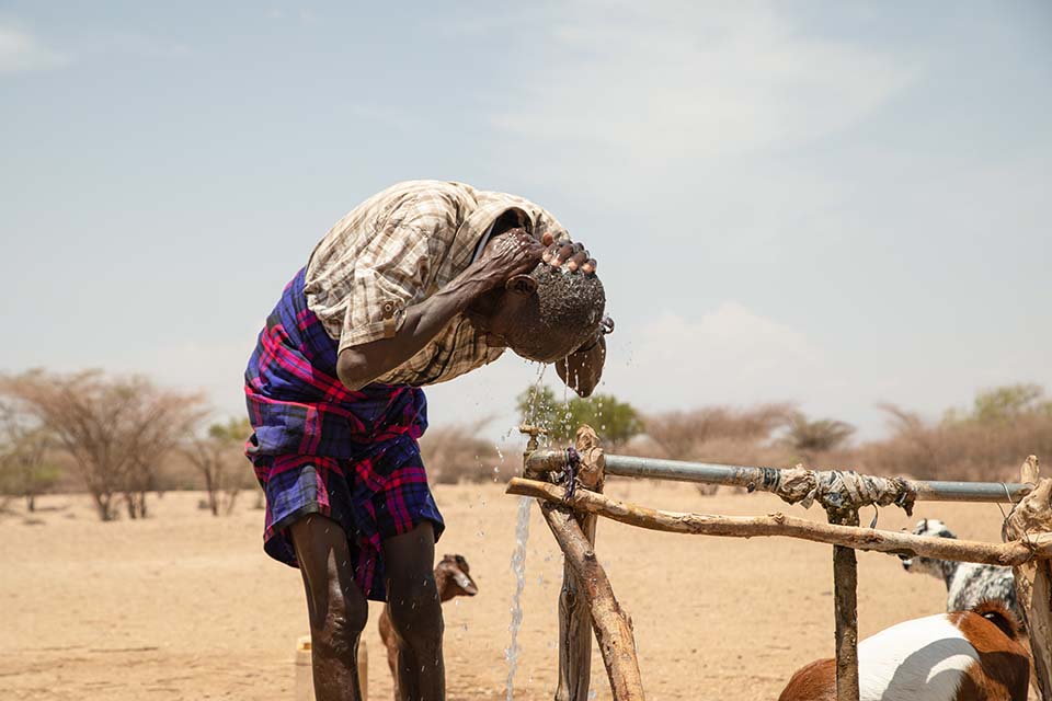 man cools off in Kenya at water point