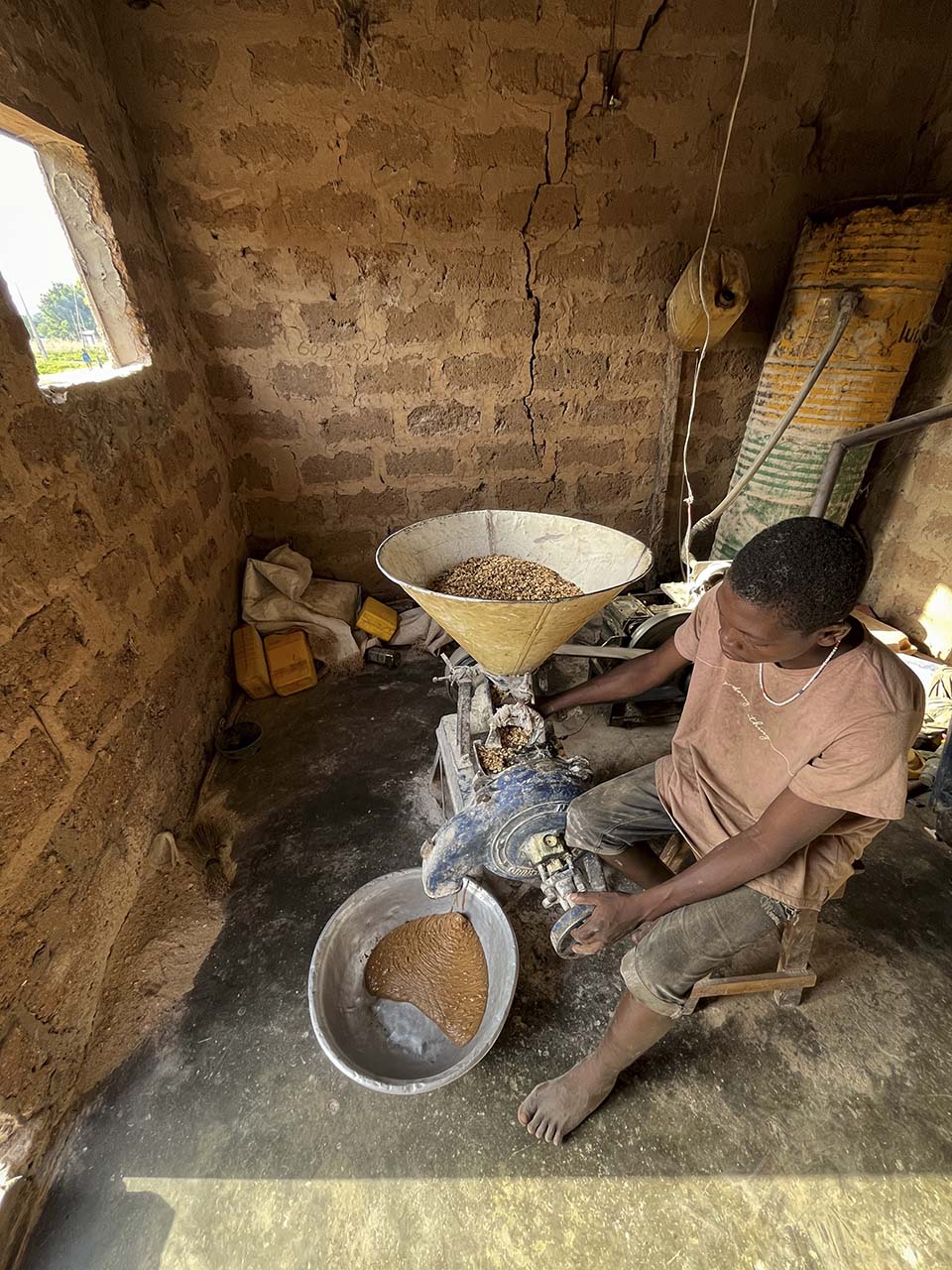 man grinds peanuts in Benin