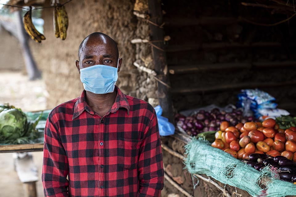 man outside vegetable stand in Kenya