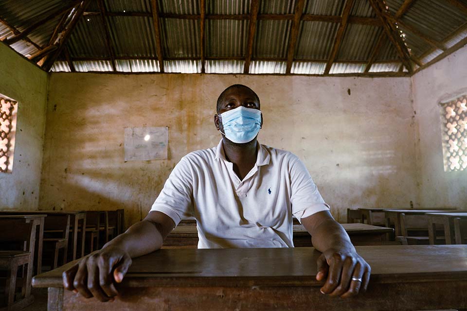 man wearing mask seated inside school room in Guinea Bissau 