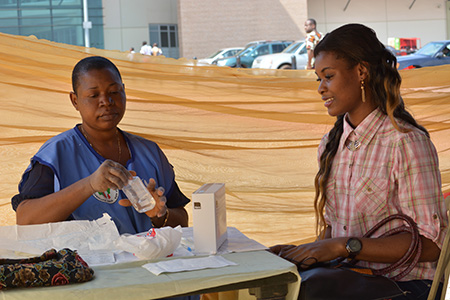 CRS volunteer Ngozi Ifediagwu, left, teaches people about HIV and AIDS, and tests them for the virus. Photo by George Akor/CRS