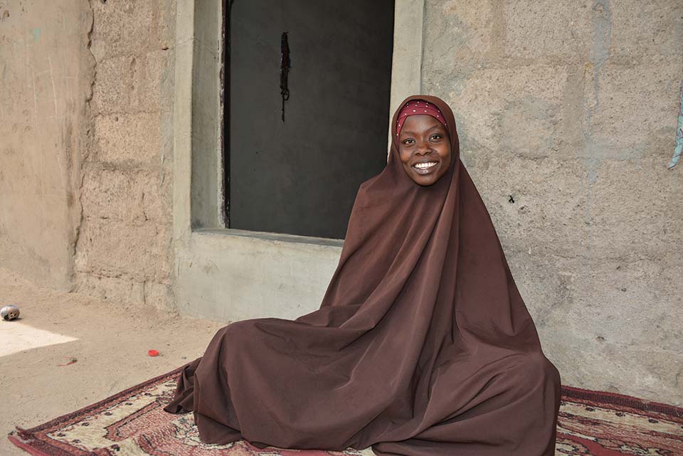 woman sits outside home in Nigeria