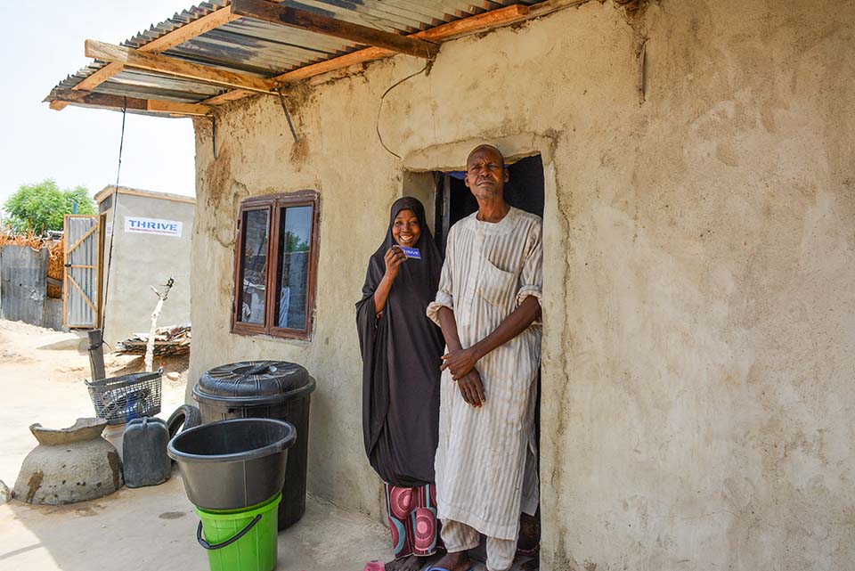 couple stands together outside home in Nigeria