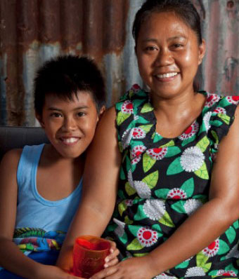 Jihan Refuelo, seated center, sells home-cooked meals from a makeshift stall to try to make ends meet. She lost her home and job in Typhoon Haiyan. Photo by Laura Elizabeth Pohl for CRS
