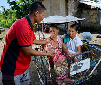 Ric De Veyra helps Florencia Lluvioso exit his bicycle rickshaw, assisted by Velma Lluviso, daughter of Florencia. De Veyra helped his entire community during recovery from Typhoon Haiyan. Charlie David Martinez for CRS