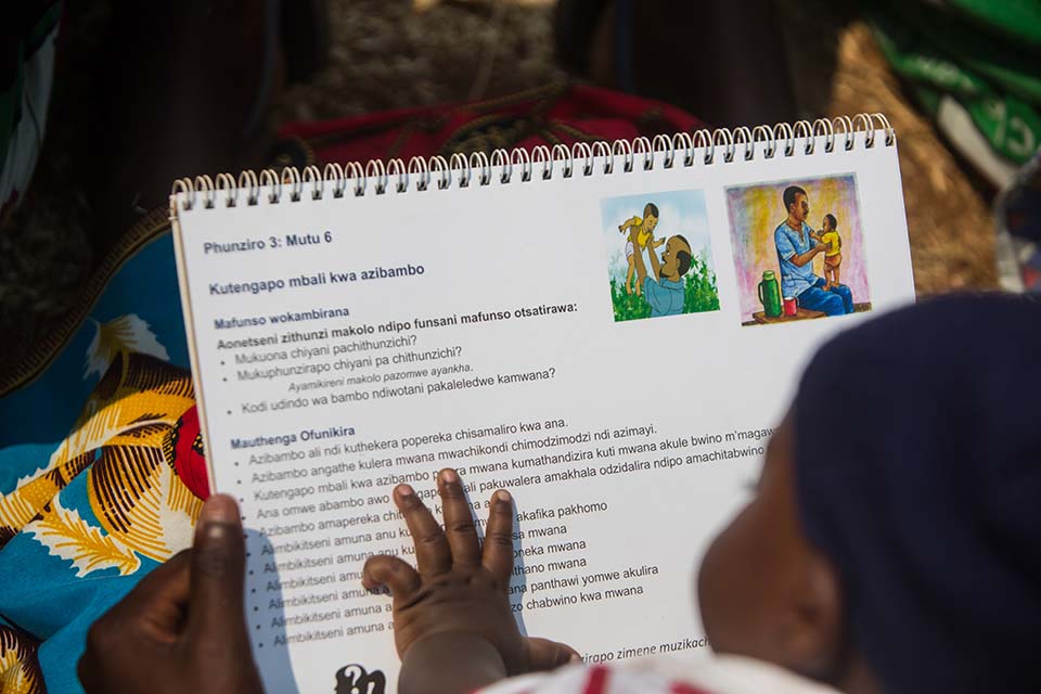 baby looks at book in Malawi