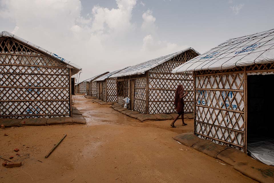 a woman walks among Rohingya camp shelters in Bangladesh