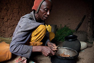 Dominique Mazimpaka prepares lunch. Before joining the Keurig Green Mountain-CRS program for coffee growers, his family ate only beans and potatoes. Now they eat other vegetables and can afford cooking oil too. Photo by Laura Elizabeth Pohl for CRS.