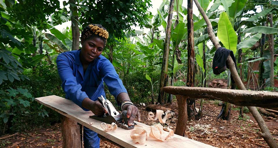 Rwandan uses a hand plan to true a board