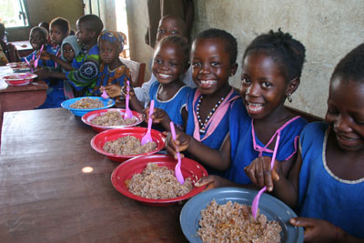 Students at Gberia Timbako primary school in Sierra Leone eat food delivered by CRS along with books, desks and school supplies. Photo by Lane Hartill/CRS